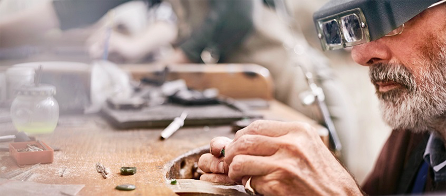 Photo of technician in goggles working at a workbench.